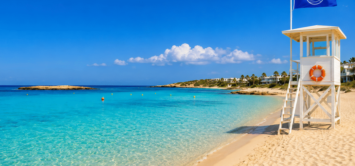 Blue Flag beach in Ayia Napa with crystal-clear turquoise water, golden sand and a lifeguard tower.